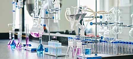 Two empty beakers standing next to glassware equipment for chemical experiments on workplace of biotechnologist or scientist