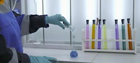 Woman conducts laboratory experiments and analyzes. Clip. Woman looks at chemical liquid in laboratory. Industrial laboratory with workers and chemicals in test tubes.
